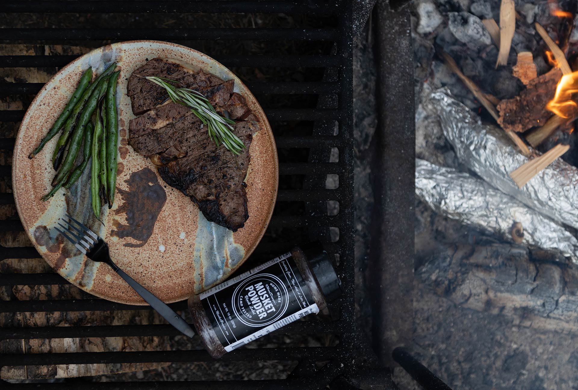 Photo of Black label on a grill next to a plate of steak and peas